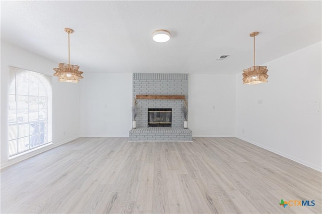 unfurnished living room featuring light wood-type flooring, visible vents, baseboards, and a fireplace