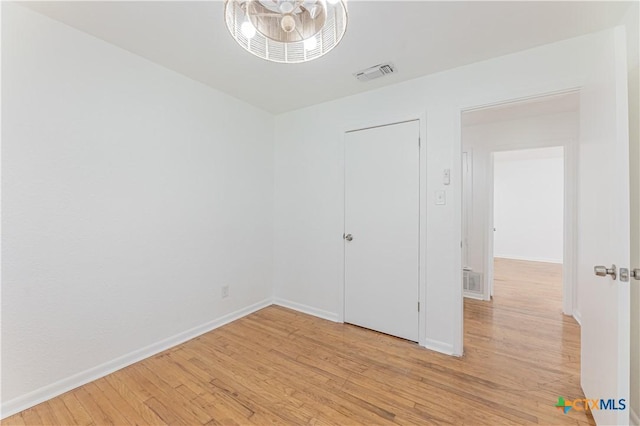 spare room with baseboards, visible vents, and light wood finished floors