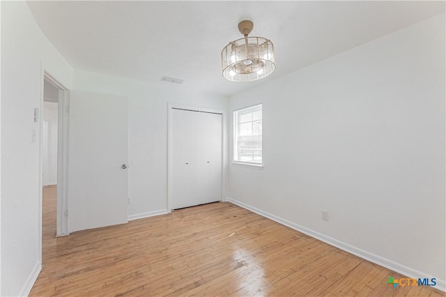 unfurnished bedroom with a closet, visible vents, light wood-type flooring, and baseboards