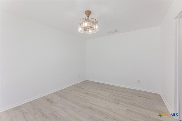 empty room featuring light wood-type flooring, baseboards, and visible vents