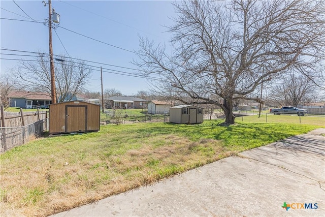 view of yard featuring a storage shed, fence, and an outdoor structure