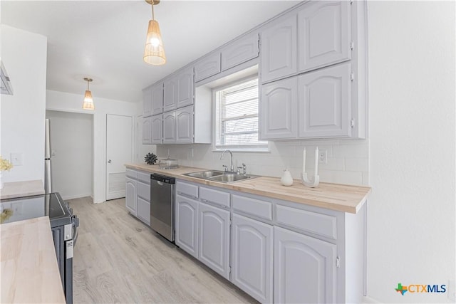 kitchen featuring a sink, backsplash, stainless steel appliances, butcher block counters, and light wood finished floors