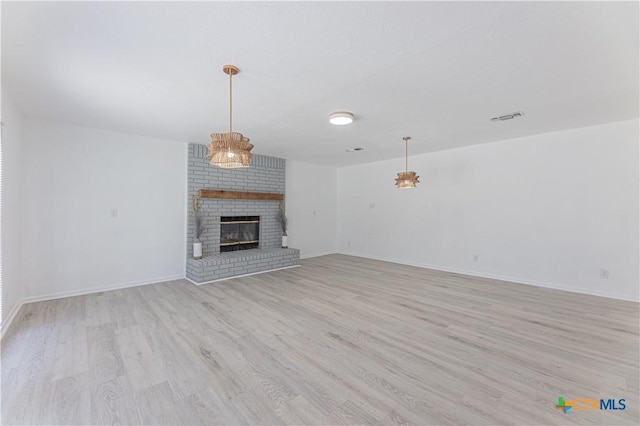 unfurnished living room with visible vents, baseboards, a fireplace, and light wood finished floors