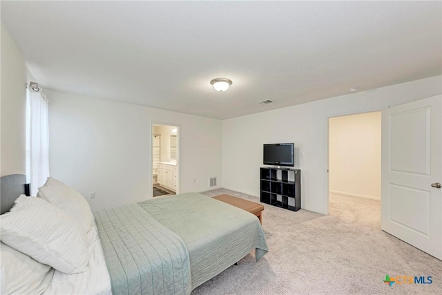 bedroom featuring light colored carpet and ensuite bath