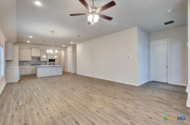 2055 Stephanie Ave, New Braunfels, TX 78132 - unfurnished living room featuring light wood-type flooring, a ceiling fan, a chandelier, baseboards, and recessed lighting
