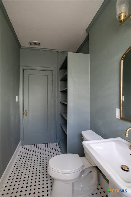 bathroom featuring toilet, ornamental molding, and sink