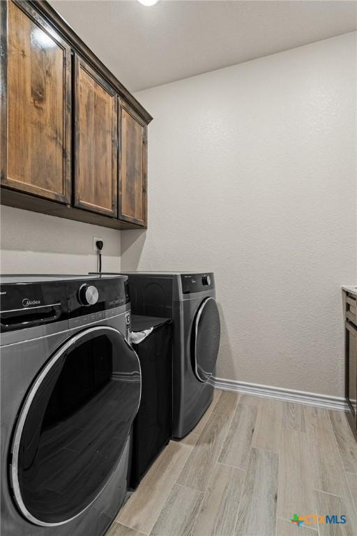 clothes washing area with cabinets and washing machine and clothes dryer