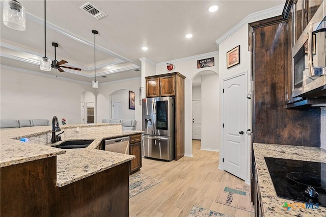 kitchen featuring stainless steel appliances, crown molding, hanging light fixtures, and light stone countertops