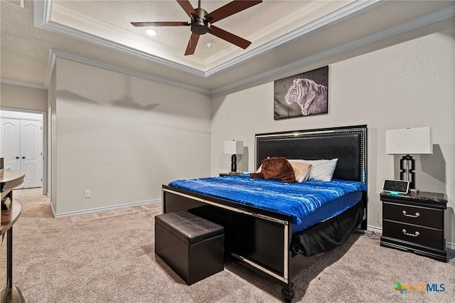 bedroom with ceiling fan, a raised ceiling, carpet flooring, a textured ceiling, and ornamental molding