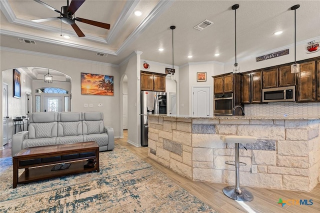 kitchen with light stone countertops, pendant lighting, stainless steel appliances, tasteful backsplash, and ceiling fan