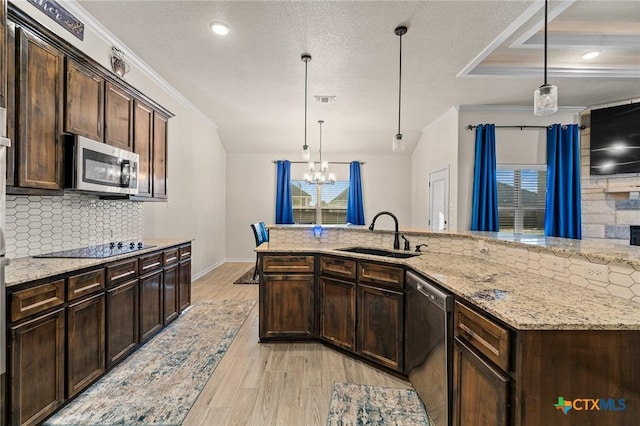 kitchen with an inviting chandelier, stainless steel appliances, decorative light fixtures, and sink