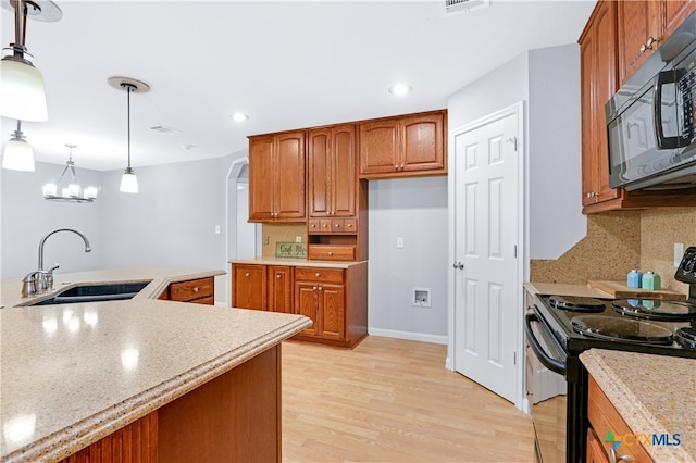 kitchen featuring backsplash, sink, decorative light fixtures, light hardwood / wood-style floors, and black / electric stove