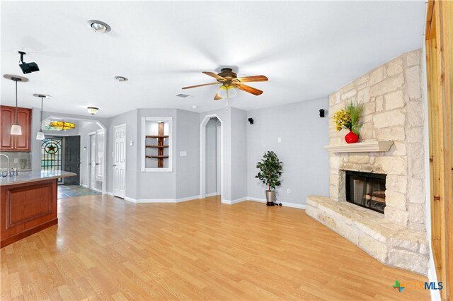 unfurnished living room with a fireplace, light hardwood / wood-style floors, and ceiling fan