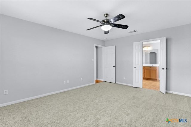 unfurnished bedroom with connected bathroom, ceiling fan, and light carpet