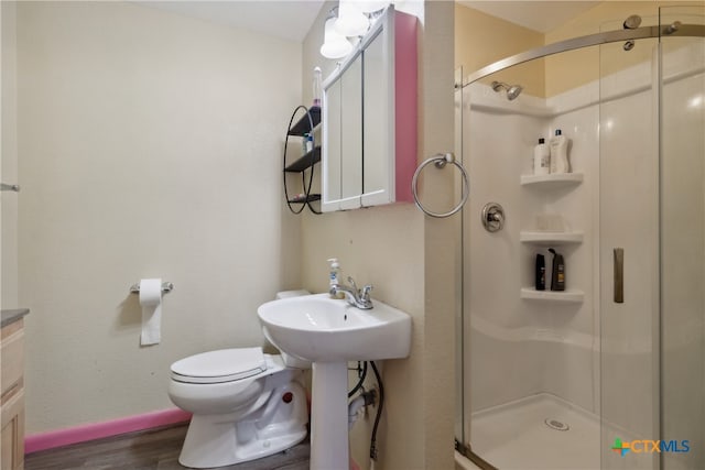 bathroom with toilet, an enclosed shower, and hardwood / wood-style flooring