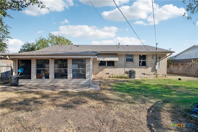 back of house with central AC unit and a lawn