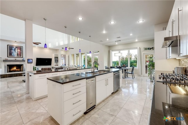 kitchen featuring white cabinets, pendant lighting, sink, and an island with sink