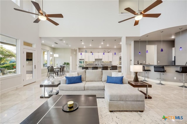 living room featuring ceiling fan, light tile patterned floors, and a high ceiling