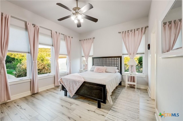 bedroom with multiple windows, light hardwood / wood-style floors, and ceiling fan