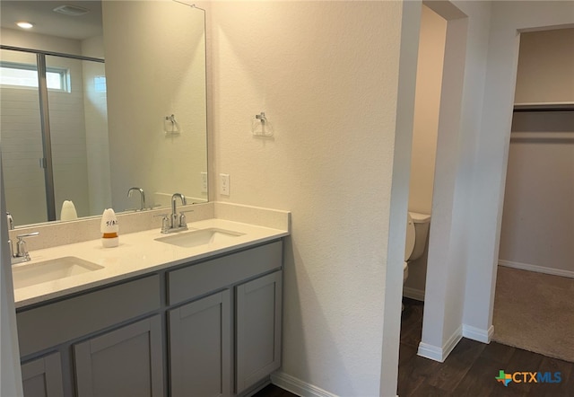 19712 Abigail Fillmore Rd, Manor, TX 78653 - bathroom featuring double vanity, a spacious closet, toilet, wood finished floors, and a stall shower
