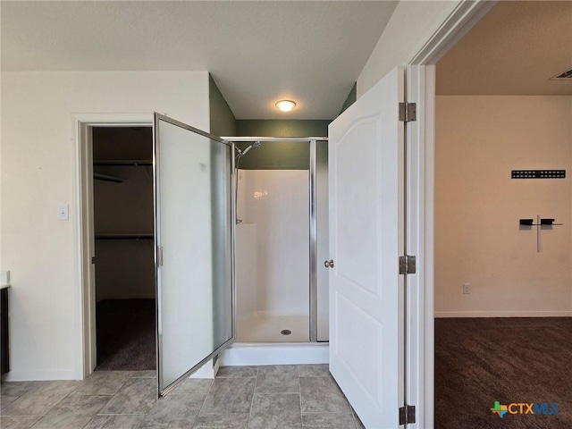 full bath featuring a spacious closet, baseboards, and a shower stall