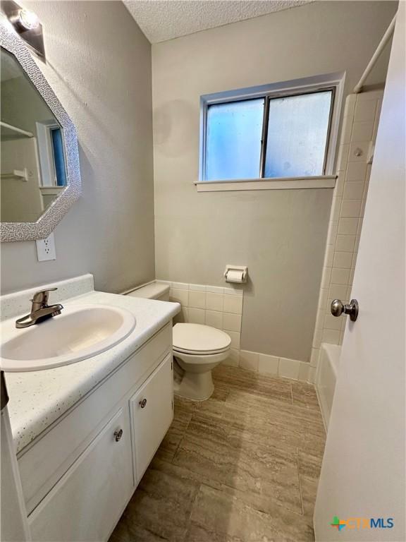 5407 Shirley St, Baytown, TX 77521 - bathroom with a textured ceiling, vanity, toilet, and  shower combination