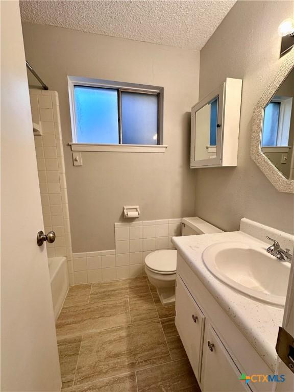 5407 Shirley St, Baytown, TX 77521 - full bath with a textured ceiling, toilet, vanity, tile patterned flooring, and tub / shower combination