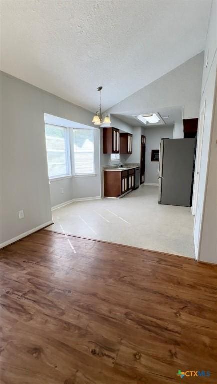 5407 Shirley St, Baytown, TX 77521 - unfurnished living room featuring baseboards, light wood-style floors, a textured ceiling, a chandelier, and lofted ceiling
