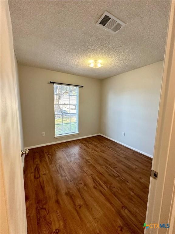5407 Shirley St, Baytown, TX 77521 - empty room featuring a textured ceiling, dark wood-type flooring, and baseboards