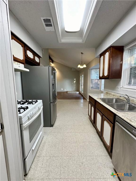 5407 Shirley St, Baytown, TX 77521 - kitchen with stainless steel dishwasher, a sink, white range with gas stovetop, light flooring, and a chandelier