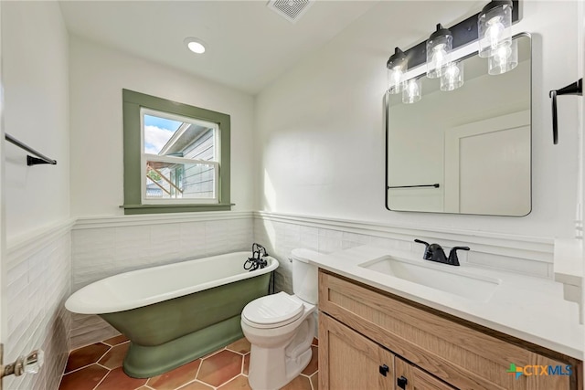 bathroom with a tub, vanity, tile patterned floors, toilet, and tile walls