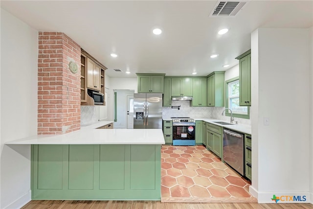 kitchen with stainless steel appliances, backsplash, sink, kitchen peninsula, and light hardwood / wood-style flooring