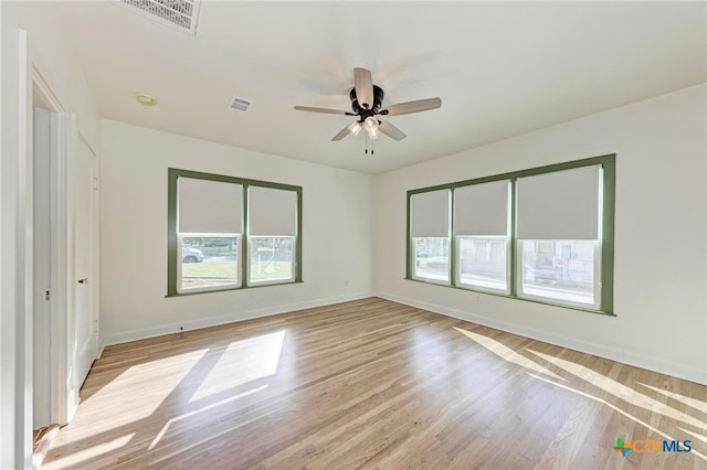 empty room with a wealth of natural light, ceiling fan, and light hardwood / wood-style floors