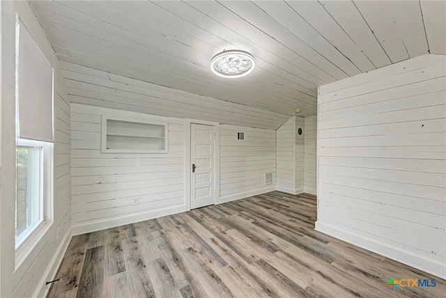 additional living space featuring hardwood / wood-style floors, lofted ceiling, and wooden walls