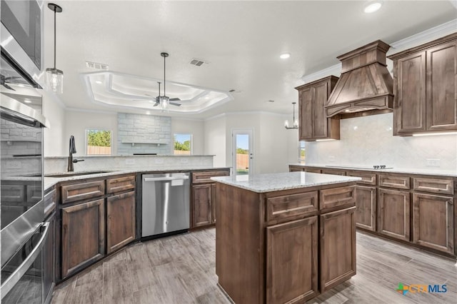 kitchen featuring stainless steel dishwasher, sink, hanging light fixtures, and a tray ceiling