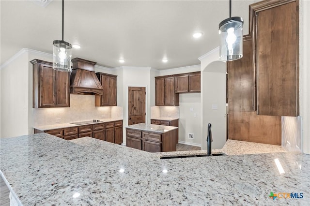 kitchen with premium range hood, black electric cooktop, sink, and hanging light fixtures