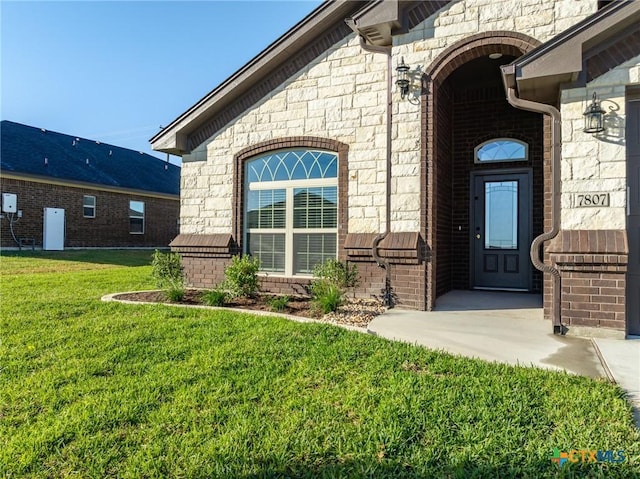 view of exterior entry featuring a lawn