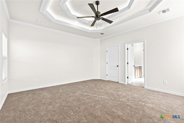 spare room featuring carpet flooring, ceiling fan, ornamental molding, and a tray ceiling