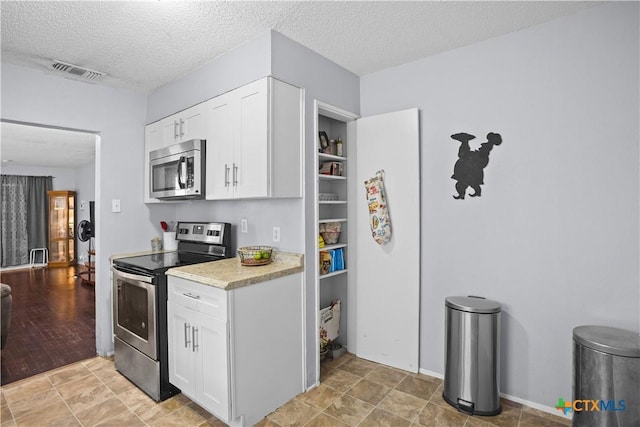 138 Antrim Dr, San Antonio, TX 78218 - kitchen featuring appliances with stainless steel finishes, light countertops, white cabinetry, and a textured ceiling