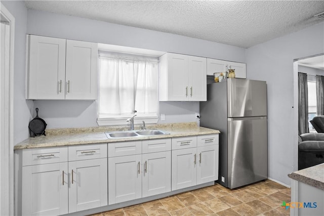 138 Antrim Dr, San Antonio, TX 78218 - kitchen with freestanding refrigerator, a sink, white cabinetry, a textured ceiling, and light countertops
