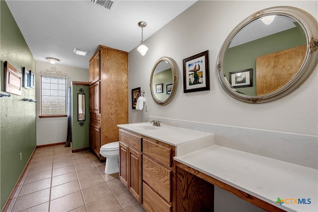 bathroom with toilet, vanity, and tile patterned floors