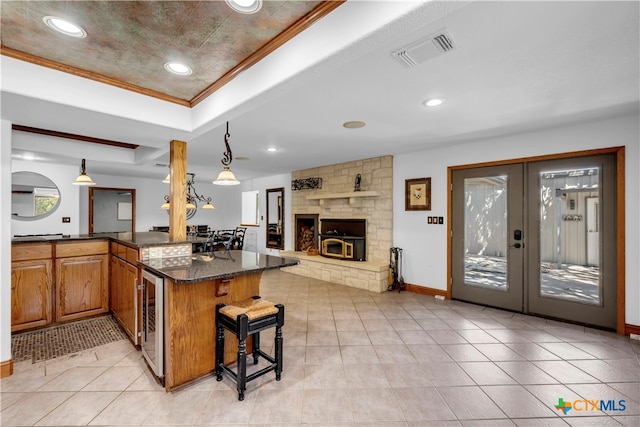 kitchen with french doors, crown molding, hanging light fixtures, a breakfast bar area, and dark stone countertops