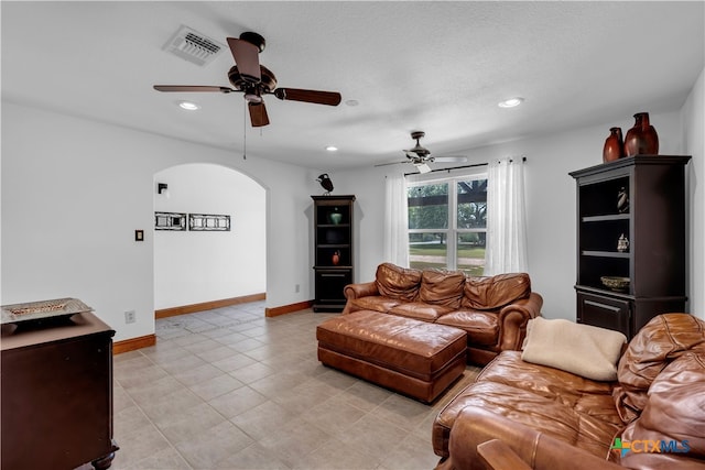 living room featuring a textured ceiling, light tile patterned floors, and ceiling fan