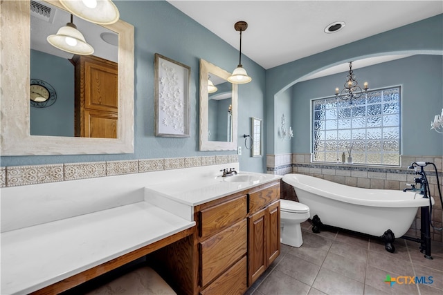 bathroom featuring tile walls, tile patterned flooring, a notable chandelier, a bathing tub, and vanity