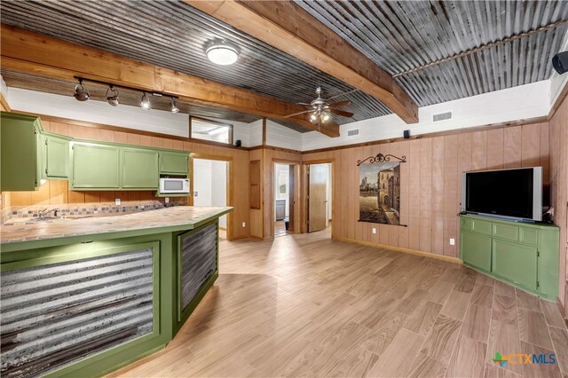 kitchen featuring wood walls, light hardwood / wood-style floors, beamed ceiling, green cabinets, and ceiling fan