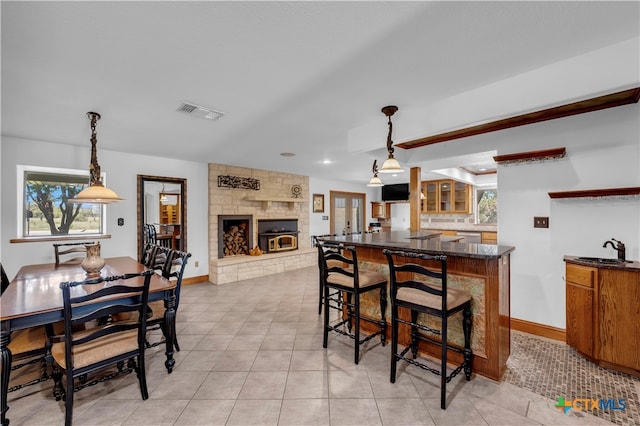 kitchen with pendant lighting, a large fireplace, a breakfast bar area, and light tile patterned floors