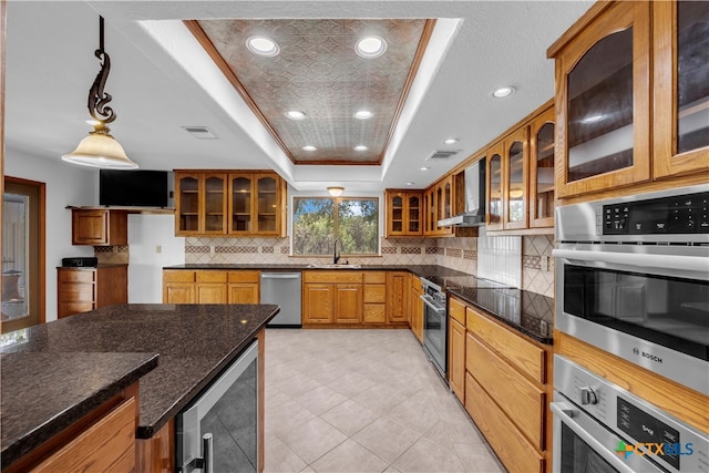 kitchen with wine cooler, dark stone counters, wall chimney range hood, a raised ceiling, and pendant lighting