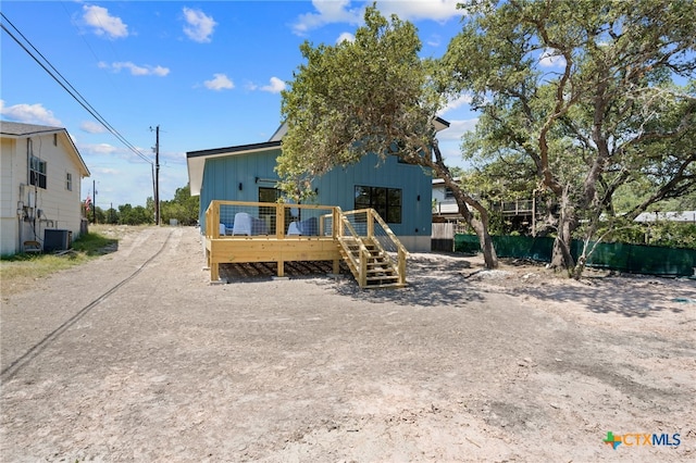 rear view of property with a wooden deck, central AC unit, and fence