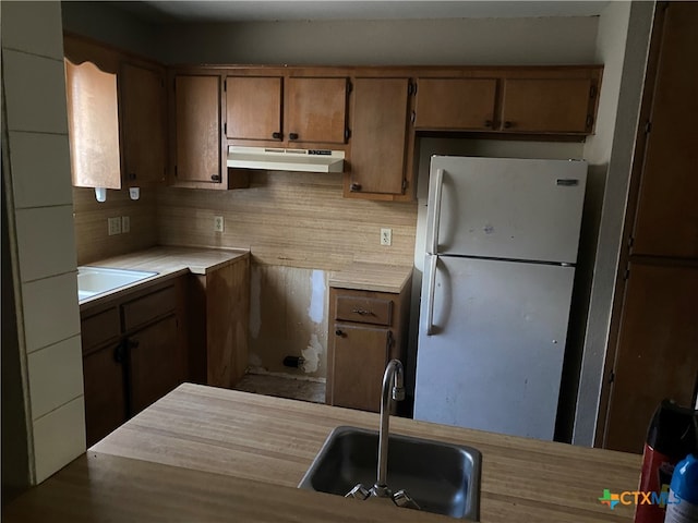 kitchen with wood-type flooring, sink, white refrigerator, and tasteful backsplash