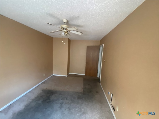 spare room with a textured ceiling, dark carpet, and ceiling fan